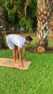 Hintli genç adam yoga eğitimi alıyor. Parkın minderinde spor salonu. Dışarıda. Sağlıklı olmak için rahatla. Yaz mevsiminde kanarya adalarında daha iyi hareket edebilme egzersizleri.