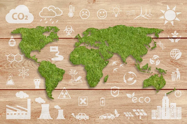 Ecology concept: sustainable World. A green grass textured World map above a brown wood planks panel, with several white ecology icons superimposed on background.