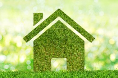 Ekoloji konsepti: sürdürülebilir ev. Yeşil bokeh arkaplanda çimen desenli bir ev