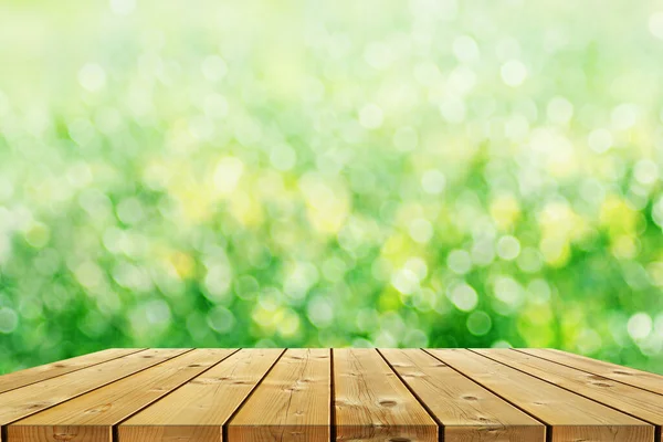 Ecology background: a brown empty wood planks table on green natural bokeh background.