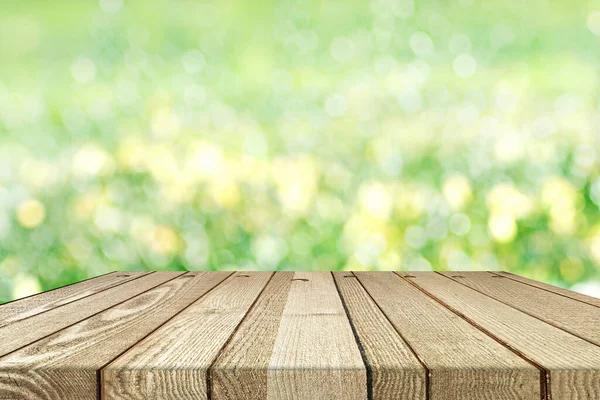 Ecology background: a brown empty wood planks table on green natural bokeh background.