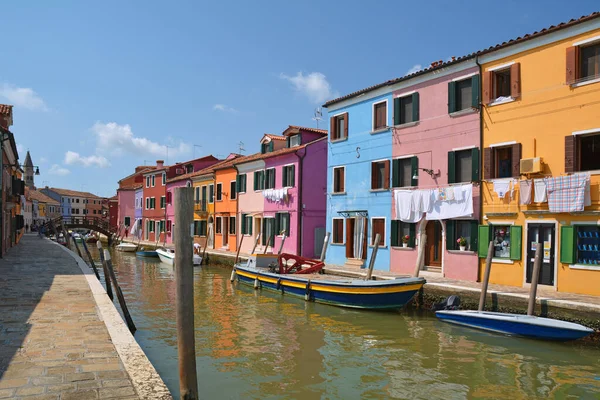 stock image Burano postcard. Colorful houses of Burano island. Multicolored buildings on fundament embankment of narrow water canal with fishing boats in sunny day, Venice Province, Veneto Region, Northern Italy. 