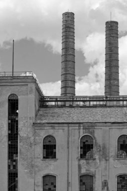 İki bacası ve kırık camları olan eski bir fabrikanın monokromatik görüntüsü