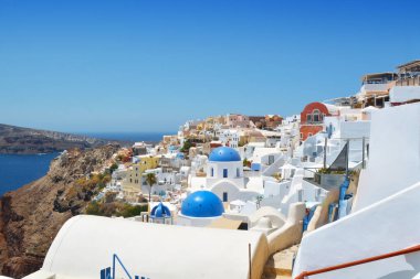 Yunanistan 'ın Santorini adasındaki Oia köyü. Caldera, Cyclades adaları üzerinde mavi kubbeleri olan geleneksel ve ünlü evler ve kiliseler Ege Denizi.