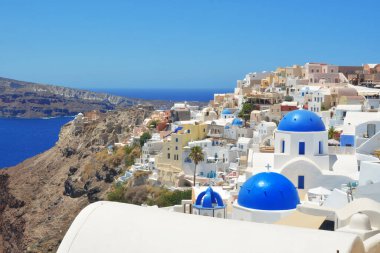 Yunanistan 'ın Santorini adasındaki Oia köyü. Caldera, Cyclades adaları üzerinde mavi kubbeleri ve beyaz evleri olan geleneksel ve ünlü kilise Ege Denizi.