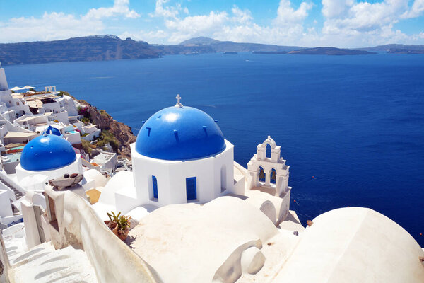 Blue Domes in Oia village on Santorini island, Greece. Traditional and famous church with blue domes and white houses over the Caldera, Cyclades islands Aegean sea.