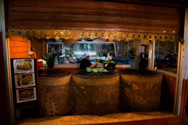 Taylandlı aşçılar, 29 Ekim 2022 'de Phrae Tayland' da Den Chai şehrinde gezginler için geleneksel kuzey lanna yemekleri pişirmek ve içki içmek için antik tuğla odun sobası kullanırlar.