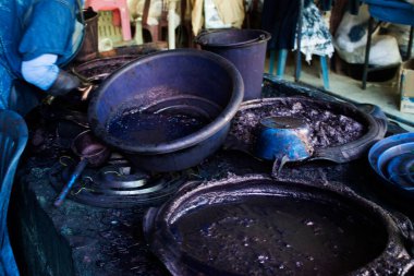 Tayland 'ın Phrae şehrinde Thung Hong köyündeki stüdyo atölyesinde Batik ikat ve çivit mavisi ile doğal renkte kravat boyası ya da maun rengi üzerinde çalışan Tayland zanaatkarlığı teknisyeni veya profesyonel sanatçı.