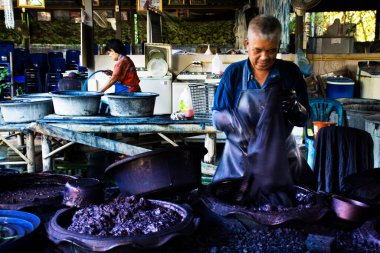 Tayland 'da 28 Ekim 2022' de Tayland Phrae, Tayland 'da Thung Hong' taki stüdyo atölyesinde Batik ikat ve çivit renginde doğal renk kravat boyası ile çalışan usta ressam veya zanaatkar.