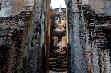 Wat Si Chum Tapınağı ve antik Pra Ajana Buddha heykellerinin antik harabeleri Tayland 'ın Sukhothai kentindeki Sukhothai Tarihi Park Dünya Mirası sahasında dua ederek seyahat ediyorlar.