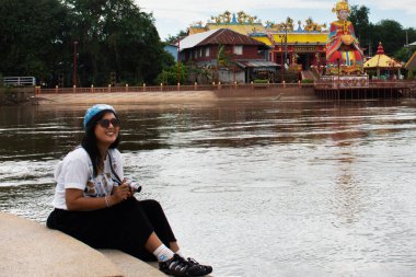 Taylandlı gezginler, 28 Ekim 2022 'de Tayland Nakhon Sawan' da Chao Mae Thapthim Çin tanrıçası Tapınağı ile Chao Phraya nehri kenarında fotoğraf çektirmek için Pa San veya Pasan köprüsünü ziyaret ederler.