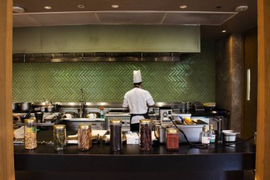 Taylandlı aşçı yemek pişiriyor ve modern mutfak tarzı lüks mutfak aletleri sergileniyor ve müşterilere sunuluyor. Bangkok Tayland 'daki restoran kafeteryasında içki ikram ediliyor.