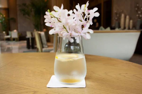 Thai restaurant manager and waiter served sparkling water with lemon to guest customer drinks on table with flower vase between wait main course in dining room at restaurant cafe in Bangkok, Thailand