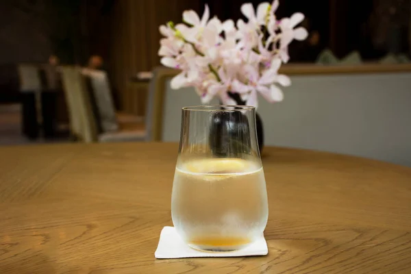 Thai restaurant manager and waiter served sparkling water with lemon to guest customer drinks on table with flower vase between wait main course in dining room at restaurant cafe in Bangkok, Thailand
