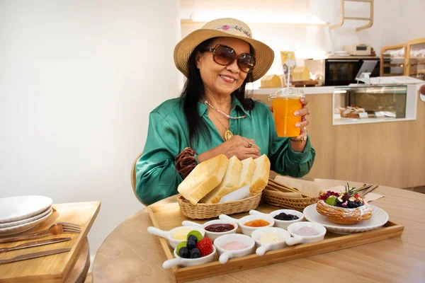Thai seniors old women people fashionable travel visit and sit relax in modern dining room of classic cafe coffee shop restaurant for eating drinks sweet snack bakery in tea time in Bangkok, Thailand