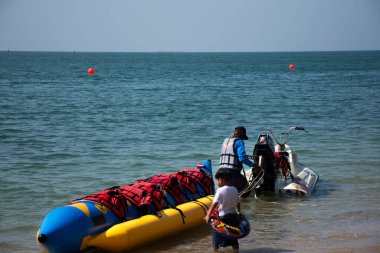 Taylandlılar ve yabancı gezginler 8 Kasım 2022 'de Chonburi Tayland' da Chon Buri şehrinde Bangsaen Sahili 'nde deniz suyunda yüzme ve jet-muzlu tekne oyunu oynamak için seyahat ederler.