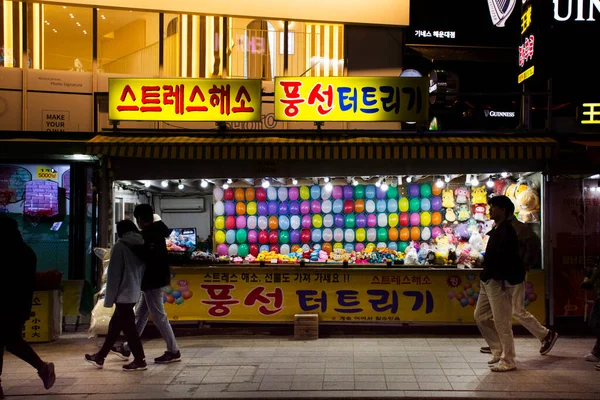 Koreliler ve yabancı gezginler için Haeundae caddesi gece pazarındaki karnaval oyunlarında 17 Şubat 2023 'te Busan, Güney Kore' de balon patlaması ve dart oyunu atari salonu.