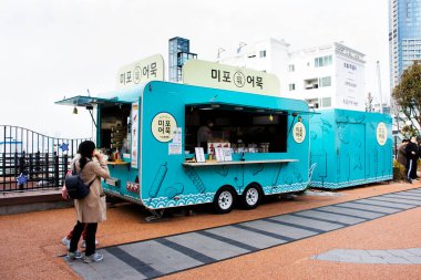 Koreli gezginler için modern vintage yemek kamyonu ve kafe kafe aracı 18 Şubat 2023 'te Güney Kore' nin Busan kentinde Haeundae Plajı 'ndaki yemek kamyonundan yemek içeceği satın alın.