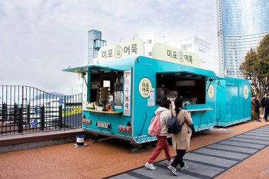 Koreli gezginler için modern vintage yemek kamyonu ve kafe kafe aracı 18 Şubat 2023 'te Güney Kore' nin Busan kentinde Haeundae Plajı 'ndaki yemek kamyonundan yemek içeceği satın alın.