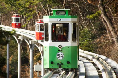 Koreli ve yabancı yolcular 18 Şubat 2023 'te Güney Kore' nin Busan kentindeki Haeundae Sahil Parkı 'na seyahat için Mipo İstasyonu' ndaki Gökyüzü Kapsülü Tramvayı Tramvayı ile seyahat ediyorlar.