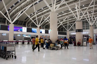 Koreli ve yabancı yolcular, 18 Şubat 2023 'te Jeju Uluslararası Havalimanı Jeju Adası, Güney Kore' deki seyahat yolculuğunda kontrol için terminalde bavullarını taşıyorlar.