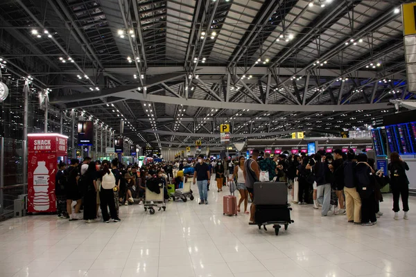 タイ人と外国人旅行者2023年2月16日にタイのバンコクでスワンナプーム国際空港での旅行の訪問の旅でチェックするためにターミナルで手荷物を運ぶ歩いて乗客 — ストック写真