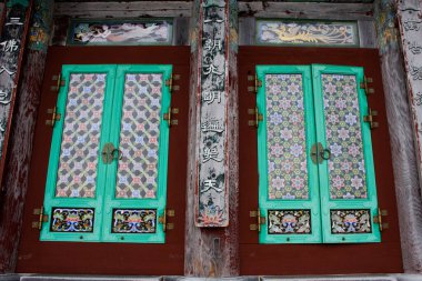 18 Şubat 2023 'te Busan veya Pusan, Güney Kore' de Haedong Yonggungsa tapınağındaki Daeungjeon ana binasının antik Kore mimarisinde ahşap kapı ve sanat eseri oyulmuş.