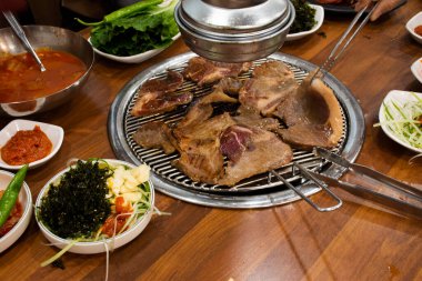 Geleneksel Kore gurmesi Jeju Adası 'nın kara domuzu ızgara ızgara domuz eti ve Kore halkı için baharatlı meze Güney Kore' deki yerel bir restoranda yemek yer.