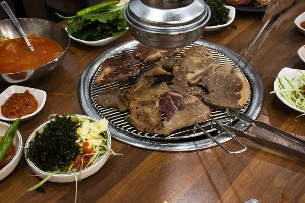 韓国の伝統的な韓国料理済州島の黒豚の焼き肉と韓国人の調味料サイドディッシュ韓国で地元のレストランでドリンク料理を食べる — ストック写真
