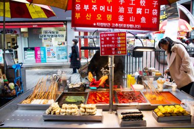 Yerel işportacılar, 18 Şubat 2023 'te Güney Kore' nin Busan kentindeki Nampo dong veya Gwangbok dong 'a gidip içki içen gezginler için sokak yemekleri pazarındaki geleneksel Kore gurmesini oyalıyor.
