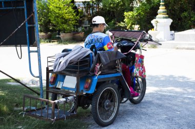 Engelli motosikleti ya da engelli Taylandlı kadınlar için üç tekerlekli tekerlekli tekerlekli tekerlekli sandalye. İnsanlar 7 Mayıs 2023 'te Nonthaburi, Tayland' da Wat Ku 'da açık otoparkında piyango bileti almak için dururlar.