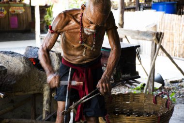 Taylandlı yaşlılar demirci ya da demirci Signburi 'deki Bang Rachan köyünün yerel demirci atölyesinde 28 Mayıs 2023' te Tayland 'ın Sing Buri kentinde antik demir zırh ve çelik metal silah yapıyor.