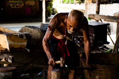 Taylandlı yaşlılar demirci ya da demirci Signburi 'deki Bang Rachan köyünün yerel demirci atölyesinde 28 Mayıs 2023' te Tayland 'ın Sing Buri kentinde antik demir zırh ve çelik metal silah yapıyor.
