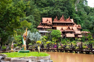 Tayland 'ın Uthai Thani kentindeki Ban Rai şehrindeki Wat Tham Khao Wong Tapınağı' nda dua eden gezginler için antik ahşap bina ve göl dağlı bahçe bahçesi.