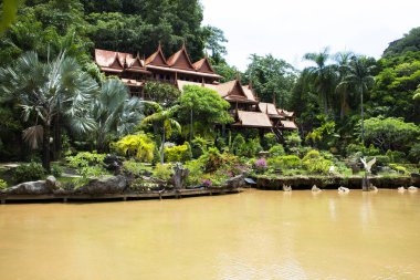 Tayland 'ın Uthai Thani kentindeki Ban Rai şehrindeki Wat Tham Khao Wong Tapınağı' nda dua eden gezginler için antik ahşap bina ve göl dağlı bahçe bahçesi.