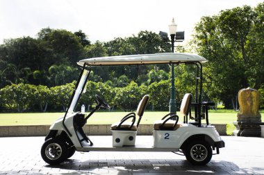 Golf arabaları elektrikli arabalar ya da elektrikli araçlar bahçe parkındaki sokak yolunda dururlar. Bekle servis. Gezginler arabayla gezerler.