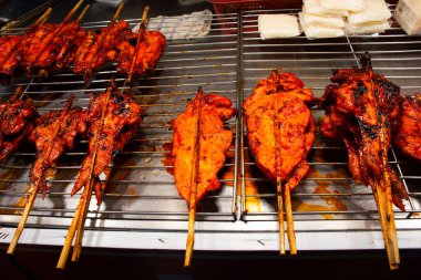 Tayland 'ın Nonthaburi kentinde düzenlenen geleneksel sokak pazarı etkinlik festivalinde Tayland' da Tayland halkı için yerel antika fırınında baharatlarla marine edilmiş terbiye edilmiş kızarmış kümes hayvanları veya kızarmış tavuk yiyor.