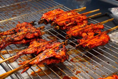 Tayland 'ın Nonthaburi kentinde düzenlenen geleneksel sokak pazarı etkinlik festivalinde Tayland' da Tayland halkı için yerel antika fırınında baharatlarla marine edilmiş terbiye edilmiş kızarmış kümes hayvanları veya kızarmış tavuk yiyor.