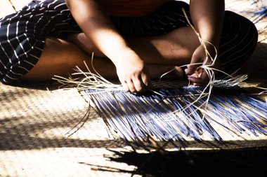 Tayland 'da Phatthalung, Tayland' da Thale Noi 'deki el sanatları atölyesinde özel el yapımı krachut ya da sedge ürünleri satmak için hasır örgü ören profesyonel bir zanaatkar teknisyen.
