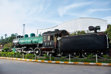 Taylandlı gezginlerin Chumphon, Tayland 'daki Chumphon tren istasyonunun antika bina retro mimarisinin önünde seyahat ettiklerini göstermek için tren yolu üzerindeki antika model yerel Bogie Steam lokomotifi.