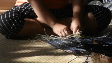 Tayland 'da Phatthalung, Tayland' da Thale Noi 'deki el sanatları atölyesinde özel el yapımı krachut ya da sedge ürünleri satmak için hasır örgü ören profesyonel bir zanaatkar teknisyen.