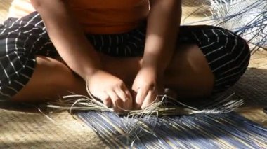 Tayland 'da Phatthalung, Tayland' da Thale Noi 'deki el sanatları atölyesinde özel el yapımı krachut ya da sedge ürünleri satmak için hasır örgü ören profesyonel bir zanaatkar teknisyen.