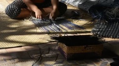 Tayland 'da Phatthalung, Tayland' da Thale Noi 'deki el sanatları atölyesinde özel el yapımı krachut ya da sedge ürünleri satmak için hasır örgü ören profesyonel bir zanaatkar teknisyen.