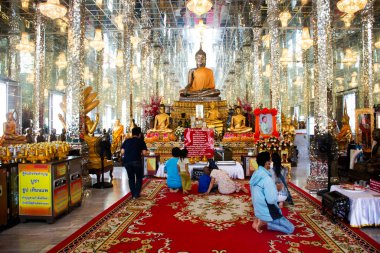 Tayland 'da, Ang Thong, Tayland' da, 31 Ekim 2023 tarihinde Angthong 'daki Wat Muang Tapınağı' nın kutsal gizemi için dua eden gezginler için antik cam ubosot salonundaki Buda heykeli.