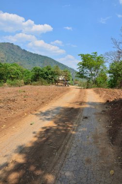 Asfalt olmayan Lateritik yol veya yanal ruj, Tayland 'ın başkenti Suphan Buri' deki Phu Toei Ulusal Parkı 'ndaki Ban Taphoen Khi köyüne araç yolculuğu için Khao Thewada Dağı' ndaki kırmızı toprak caddesini kirletti.