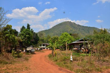 Asfalt olmayan Lateritik yol veya yanal ruj, Tayland 'ın başkenti Suphan Buri' deki Phu Toei Ulusal Parkı 'ndaki Ban Taphoen Khi köyüne araç yolculuğu için Khao Thewada Dağı' ndaki kırmızı toprak caddesini kirletti.