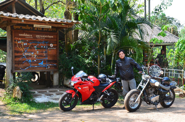 Thai man biker biking motorcycle travelers people riding motorbike travel visit Ban Taphoen Khi Village top of Khao Thewada mountain at Phu Toei National Park on May 14, 2011 in Suphanburi, Thailand