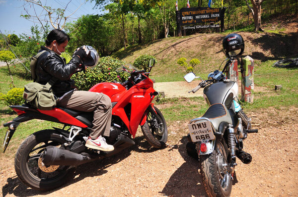 Thai man biker biking motorcycle travelers people riding motorbike travel visit Ban Taphoen Khi Village top of Khao Thewada mountain at Phu Toei National Park on May 14, 2011 in Suphanburi, Thailand