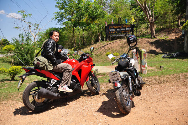 Thai man biker biking motorcycle travelers people riding motorbike travel visit Ban Taphoen Khi Village top of Khao Thewada mountain at Phu Toei National Park on May 14, 2011 in Suphanburi, Thailand