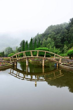 Bahçe bahçelerini ve Doi Inthanon Milli Parkı 'nın ahşap köprü gölünü Tayland' ın Chiang Mai şehrinde sabah vakti seyahat eden insanların dinlenmesi için sisli dağlarda gezin.